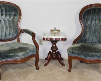 Victorian Carved Wood Frame Lady’s and Gentleman’s Chairs Blue rolled and tufted velvet upholstery  shown with White marble top small Pedestal Victorian Style Side table/plant stand, 14” W x 14” D x 19” H and gold encrusted glass 3 toed Candy Dish 