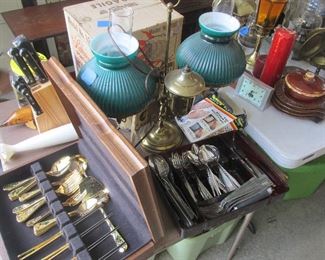 More vintage silverware sets, knife sets, stoneware, candles, clocks, brass items, and lamps.