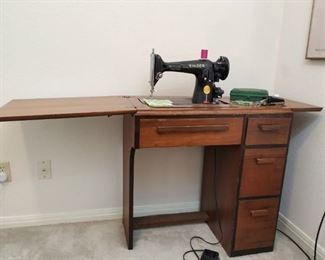 Singer sewing machine and storage cabinet with accessories and assorted presser feet. Includes buttonholer kit.
