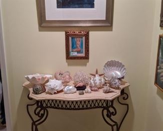 Wrought iron/travertine console table, with collection of nice seashells, original Dmitriy Proshkin nude, original seagull watercolor art, with gallery light., by Gaye Sanders Fisher.