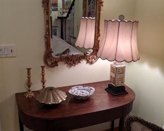 One of a pair of 1940's mahogany demilune tables, vintage Asian porcelain table lamp, pair of vintage English candlesticks, Frenchy carved wood wall mirror (not foam or composite) and cool, vintage hinged brass clamshell.