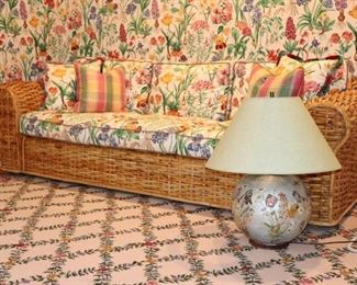Long Wicker Sofa with Floral Cushions and Lamp