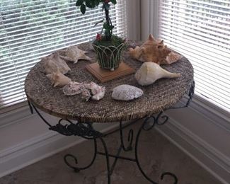 A table with black iron legs and woven top