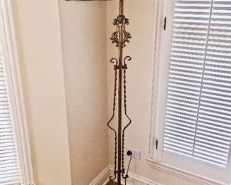 A floor lamp with rust and beige colors and a gold tone stand.