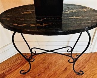 An oval side table with a black marble top.