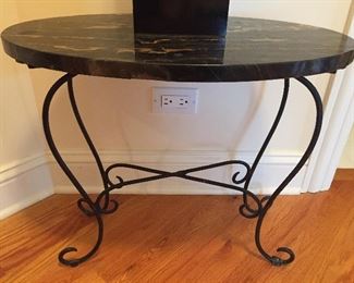 An oval side table with a black marble top.