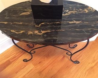 An oval side table with a black marble top.