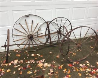 Parts of an old wooden spoked wheel and 2 sets of iron wheels with axels.