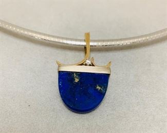 Blue lapis  and a .03 ct diamond set  in 14kt white and yellow gold pendant.