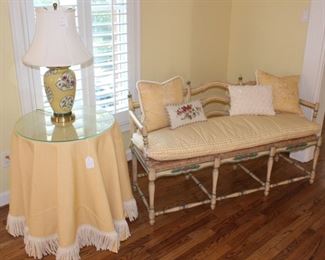 Designer cloth on round glass top table, beautiful lamp and settee.  