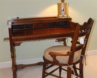 Secretary desk shown with Victorian Era chair and tole lamp.