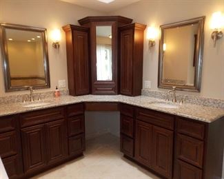 Double vanity with makeup area mirrors top of counter cabinets light fixtures sconces faucets
