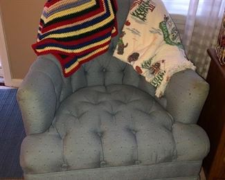 One of 2 upholstered blue print chairs w/ a crocheted runner & a woven Christmas throw on it.
