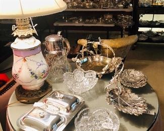 Antique lamp, round table with draped skirt and glass cover, silver and crystal serving pieces