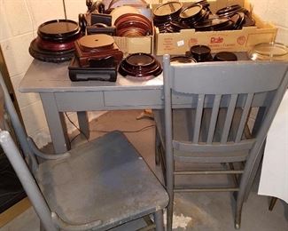 Work table, 2 chairs, and boxes of wood and black glass display stands. Most in right box are black glass