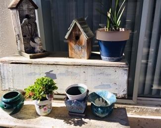 Many outdoor plants, pots of all sizes, bird houses, wind chimes, and gardening tools