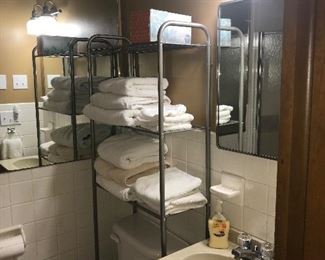 Bathroom stand, linens, sink, faucet, toilet, vanity, mirror