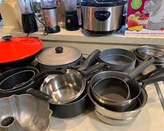 Large assortment of metal pots and pans with lids