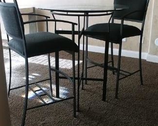 Two matching pub height glass top tables with 3 chairs each. (2 Geo print chairs and 1 black solid chair)