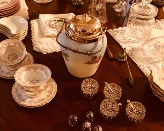 A table full of interesting items. Salts with sterling shakers and spoons. Limoges ramekins. Hand painted Victorian biscuit tin.