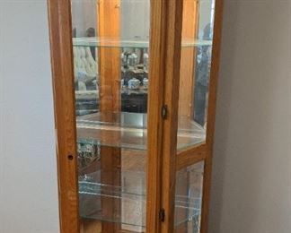 Oak lighted curio with four shelves and beveled glass.