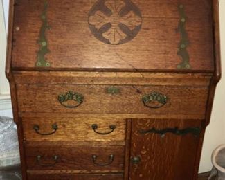 Antique secretary with large decorative brass hinges and carved floral motif. Used as a sewing machine cabinet by owner.
