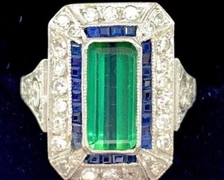 Elegant ladies platinum ring featuring a tourmaline bezel set in the center measuring 11mm x 5 mm, surrounded with channel set sapphires and further accentuated with round cut diamonds. Total estimated diamond weight .55 ct.; overall weight 6.2 gm.  Ring size: 7.25 Condition: Very good
