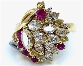 18KT yellow gold cast and assembled multi color gemstone and diamond ring. Ring features a tiered diamond bouquet set with yellow sapphire and ruby accents, supported by a lattice under gallery, completed by a three millimeter wide band. Bright polish finish. Marked "18K".  6 prong set oval mixed cut natural rubies measuring 3.00 x 2.25 x 1.46mm, exact total weight 0.61ct. Clarity is slightly included, type II, medium, strong, slightly purplish red color (GIA slpR 5/5). Cut is good. 5 prong set round mixed cut natural yellow sapphires measuring 2.30-2.20 x 1.46mm, exact total weight 0.44ct. Clarity is eye clean, type II, medium, brownish, yellow color (GIA Y 5/3). Cut is good. 16 prong set marquise and round brilliant cut diamonds exact total weight 16 Stones = 1.44ct. Clarity VS2 to S12. Color Faint to Very Light YellowTotal Weight Colored Stones 1.05 ct. Total Weight Diamonds 1.44 ct. Total Weight Ring 7.60 gm  Ring Size: 6.5 Condition: New, good workmanship AIG Appraisal Included
