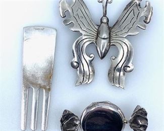 Comprising an Art Nouveau style sterling butterfly brooch, stamped Taxco Sterling, a Tiffany & Co, sterling golf divot repair tool, stamped Tiffany & Co. Sterling .925,  and a sterling locket or brooch in shape of covered hard candy. 1.22 oz. troy total wt. Butterfly 2 in. w. x 2.25 in. l. Divot Tool 2.25 in Candy Brooch 1.75 in. Condition: Very good Condition: Good
