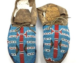 Pair of Native American Beaded Hide Moccasins. Pair of Native American Beaded Hide Moccasins, side sewn construction with rawhide sole, beaded with a horizontal stripe pattern in red, white and blue on turquoise.  10 in. l.  Condition: Loss to beadwork at toe in red center stripe.