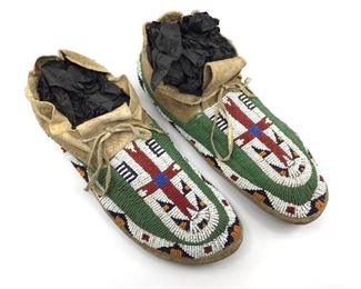 Pair of Native American Beaded Hide Moccasins, side sewn construction with rawhide sole, beaded with a central cross in red with green, yellow and blue geometric.  11. in. l.  Condition: Good