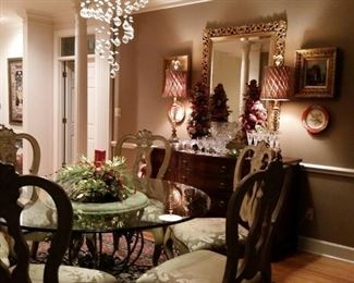 A large mahogany buffet and a large glass top pedestal table with six dining chairs.