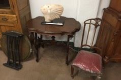 A small table with chair, and interesting statue.