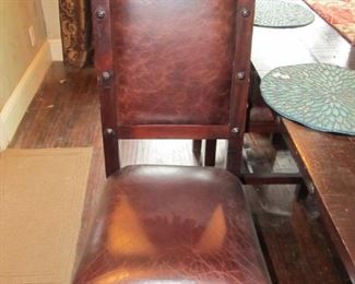 A close-up of 1 of the 4 dining chairs finished in leather.
