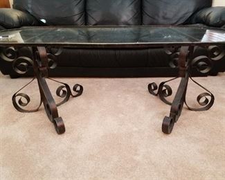 Glass top coffee table with ornate metal base 