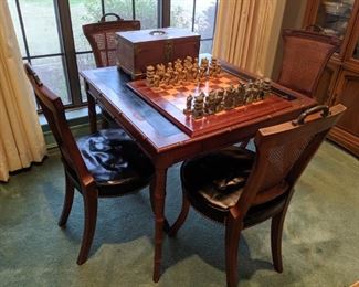L eather top game table and 4  chairs. Each seat has black leather . Brass handles on top of each chair. legs are bamboo stylel