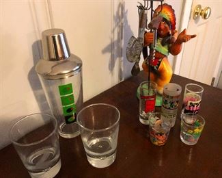 Cocktail shaker and crazy cult totem surrounded by its shot-glass followers