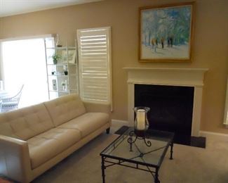 Living Room:  The recently purchased contemporary cream color leather sofa is to the left of a heavy iron coffee table with glass top.  An original painting hangs above the fireplace. Closer photos are coming up.