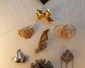 "Smalls" Area-In a Case:  A collection of costume pins including one vintage pin and one sterling pin with three chains upon which charms can be hung.