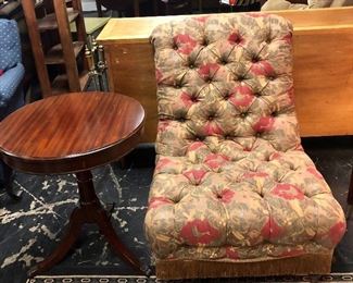 Tufted upholstered side chair with fringed bottom, on casters and antique mahogany side table