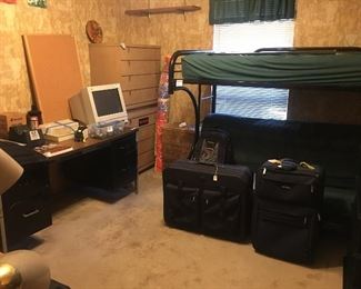 Industrial desk, blond chest of drawers, metal bunk bed, luggage, 