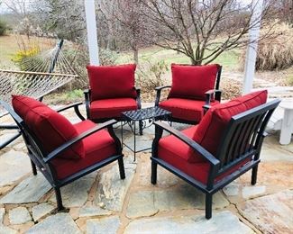 Four metal chairs with red cushions, black metal table