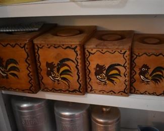 Vintage wood nesting canisters are decorated with crowing roosters in red, green and yellow. Nesting box canisters are dovetailed. 