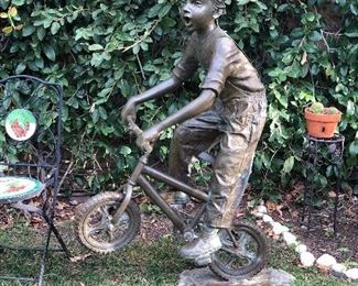 Outdoor bronze boy on bike 