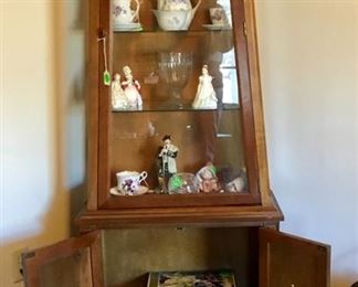 The corner curio cabinet with glass doors and bottom shelf.