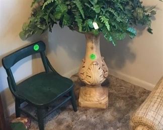 Plant stand with greenery and small child’s chair.
