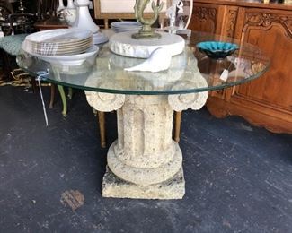 Ionic capital table base, of stone, with round glass top.