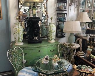 Pair of fine wrought iron foliate cafe chairs and matching table, painted commode, Iron Paladio mirror with gilded scrolling vine frame, 18th Century Blackamoor figural table of ebonized wood.
