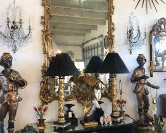 Giltwood mirror of grand scale, pair of giltwood figural blackamoors, pair of sunburst mirrors, pair of foliate giltwood table lamps, English lacquer console with inset mirrored top, pair of fine French bronze and crystal sconces, burnt bamboo settee.