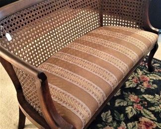 Upholstered settee with cane back and sides